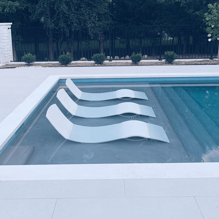 Three in-pool concrete chaise loungers on a pool tanning ledge.