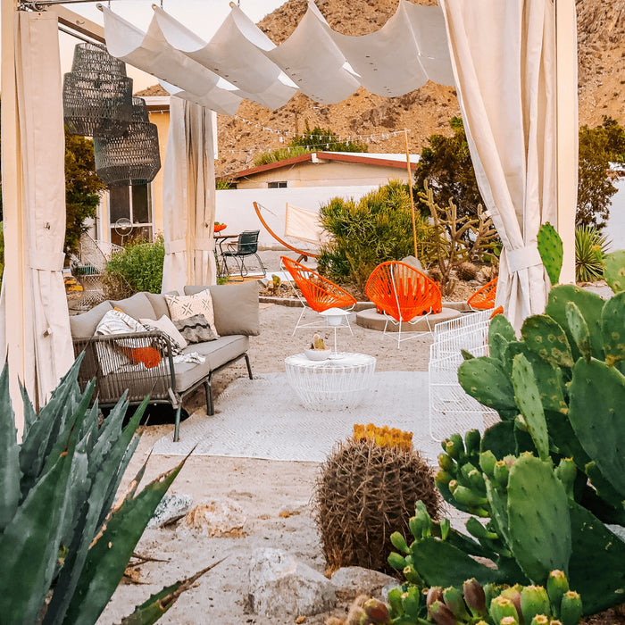 A patio adorned with a white canopy and xeriscaped cactus plants, showcasing an eco-friendly outdoor space.