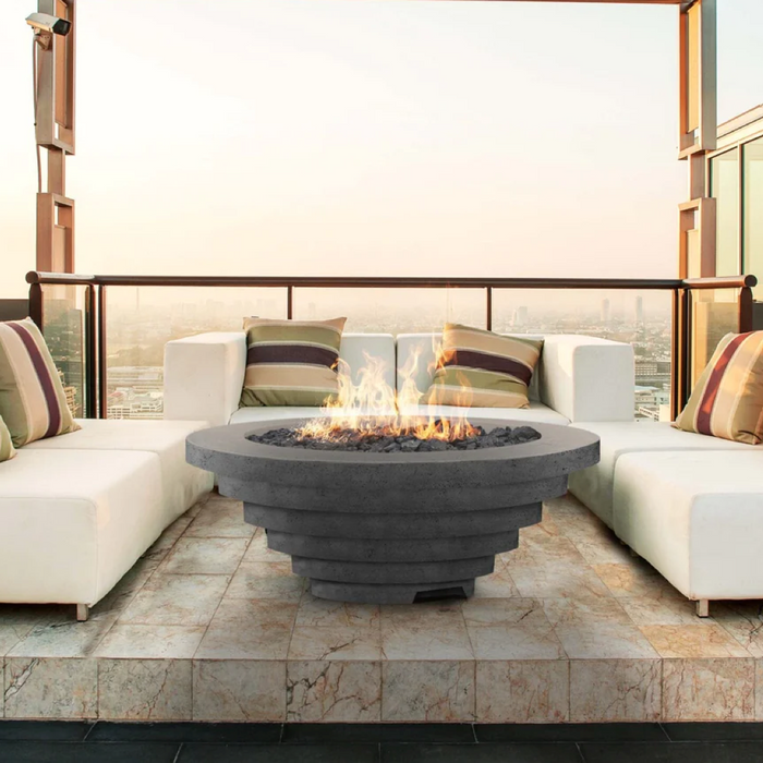 A tiered concrete fire pit flanked by white sofas is the focal point of this outdoor lounge space. 