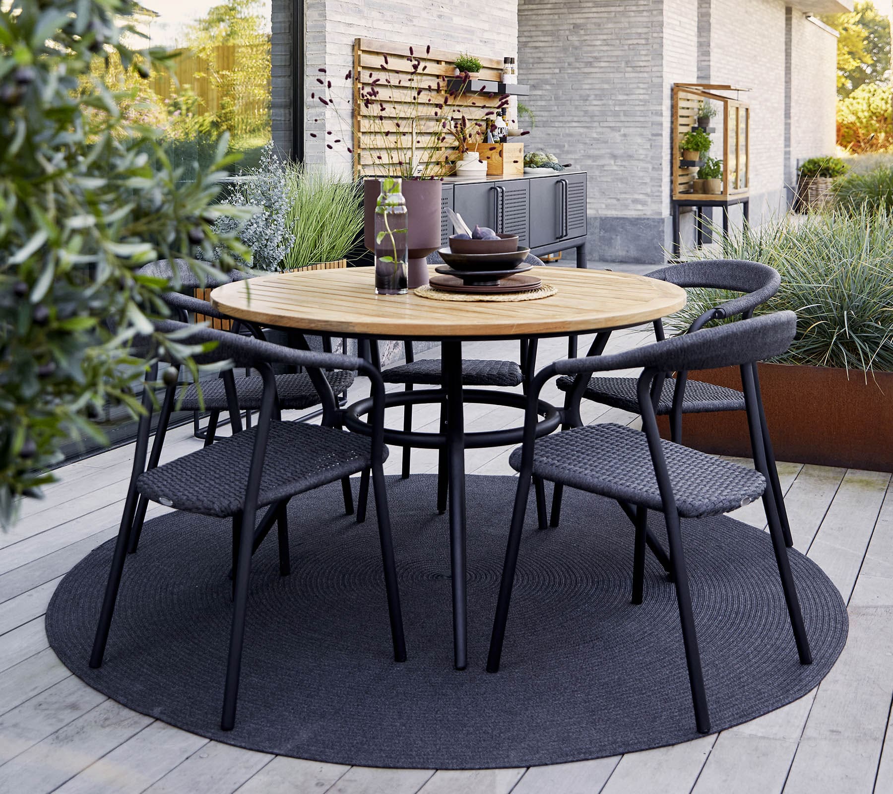Boxhill's Noble Outdoor Dining Armchair lifestyle image with teak round table at patio