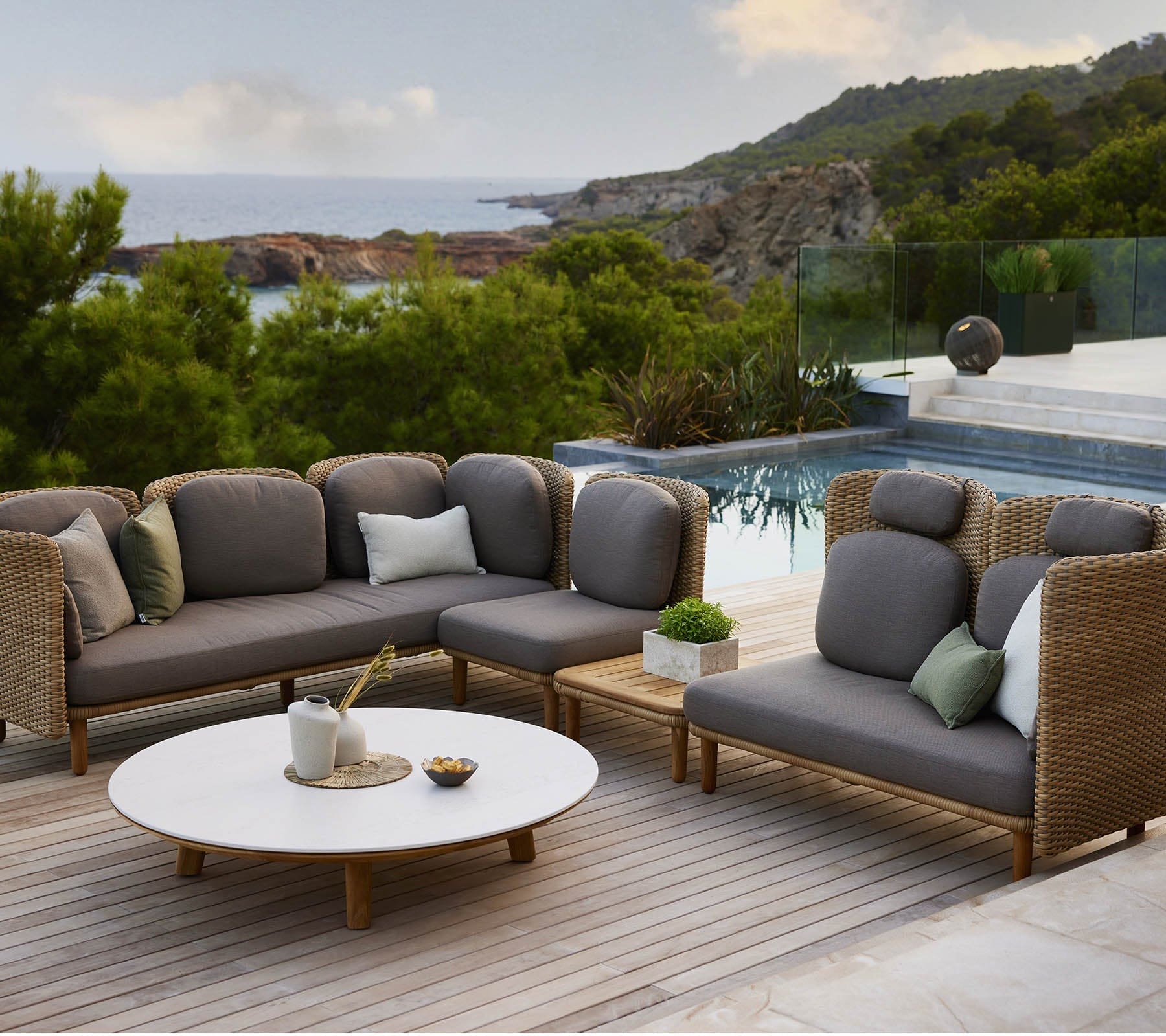 Boxhill's Arch 2-Seater Outdoor Sofa | Low Arm/Back lifestyle image beside the pool with Arch Coffee Table w/ Teak table Top
