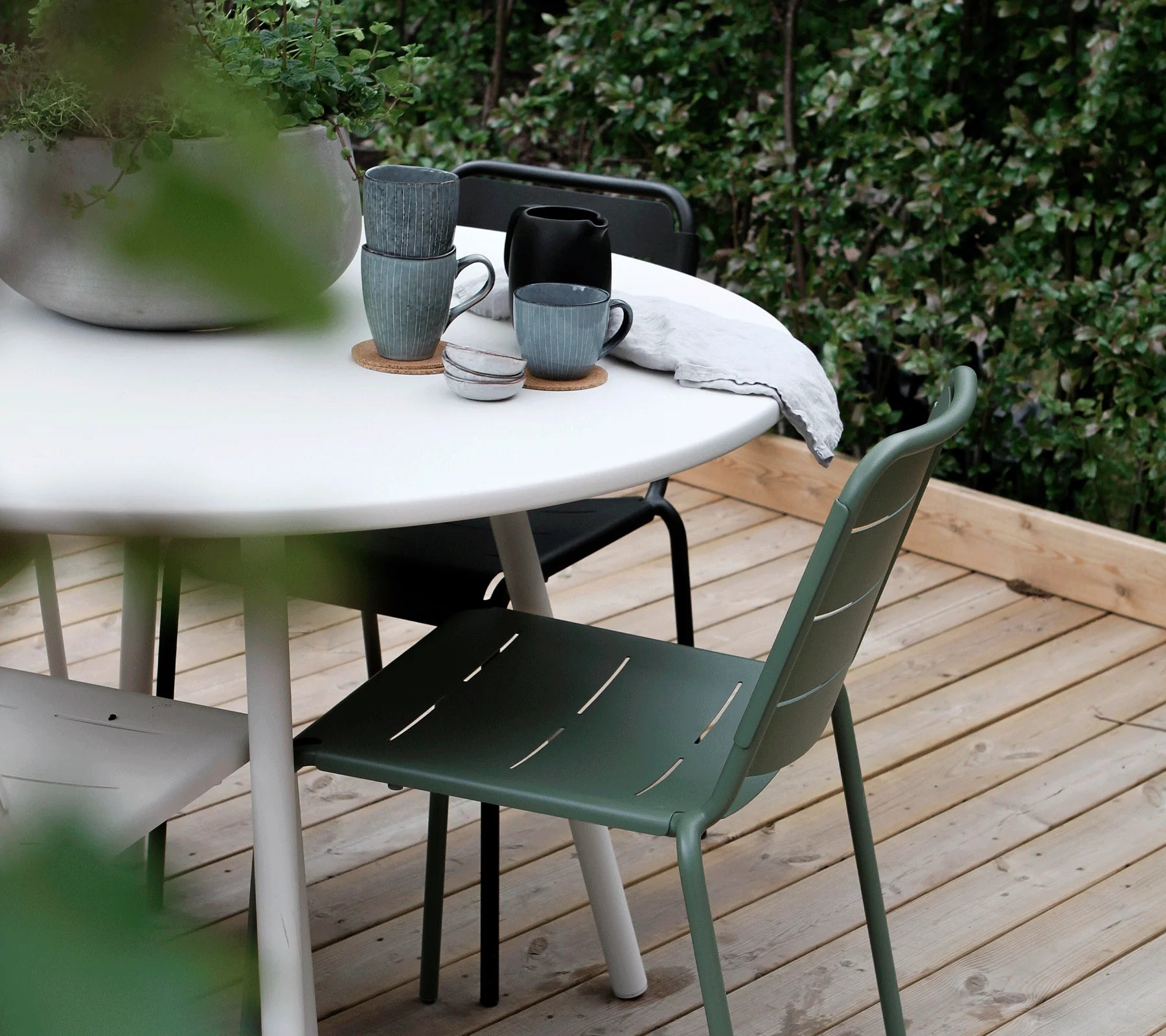 Boxhill's Area Outdoor Aluminum Dining Table White Lifestyle image on wooden platform at the garden with plant and cups on top