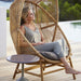 Boxhill's Hive Outdoor Hanging Chair Natural lifestyle image on wooden poolside with a woman sitting down