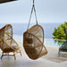 Boxhill's Hive Outdoor Hanging Chair Natural and Dusty Green Frame lifestyle image beside the pool