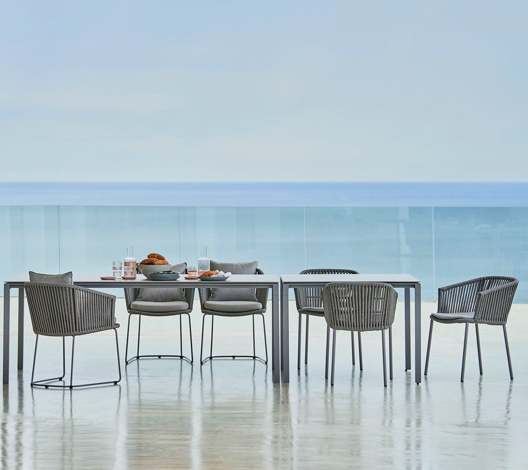 Boxhill's Moments Outdoor Dining Armchair lifestyle image with dining table at seafront