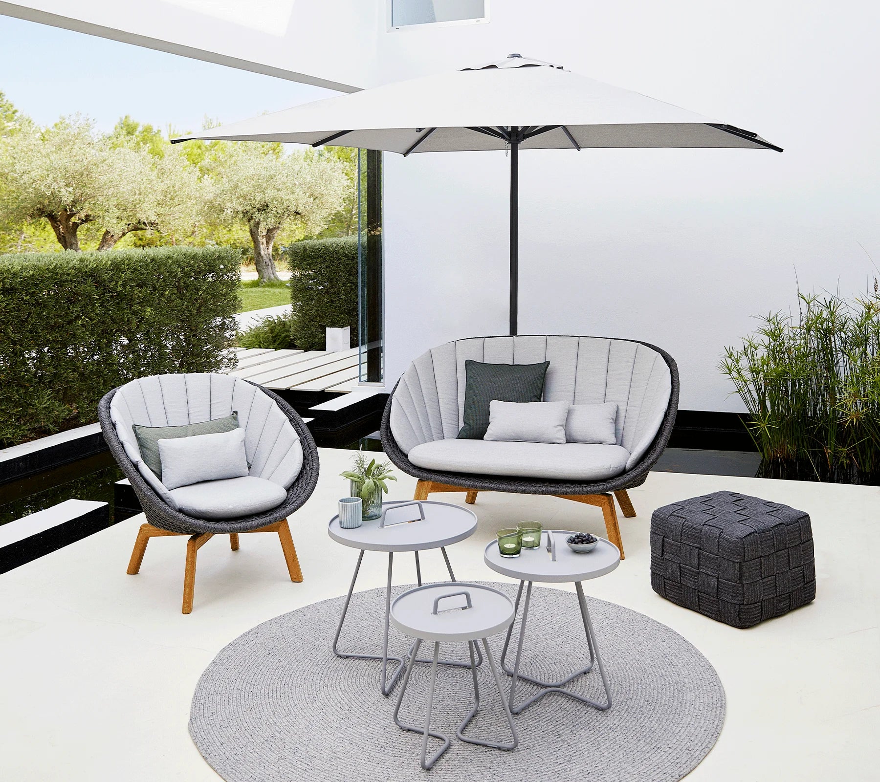 Boxhill's Peacock dark grey outdoor lounge chair with  dark grey outdoor 2-seater sofa and white parasol placed in patio
