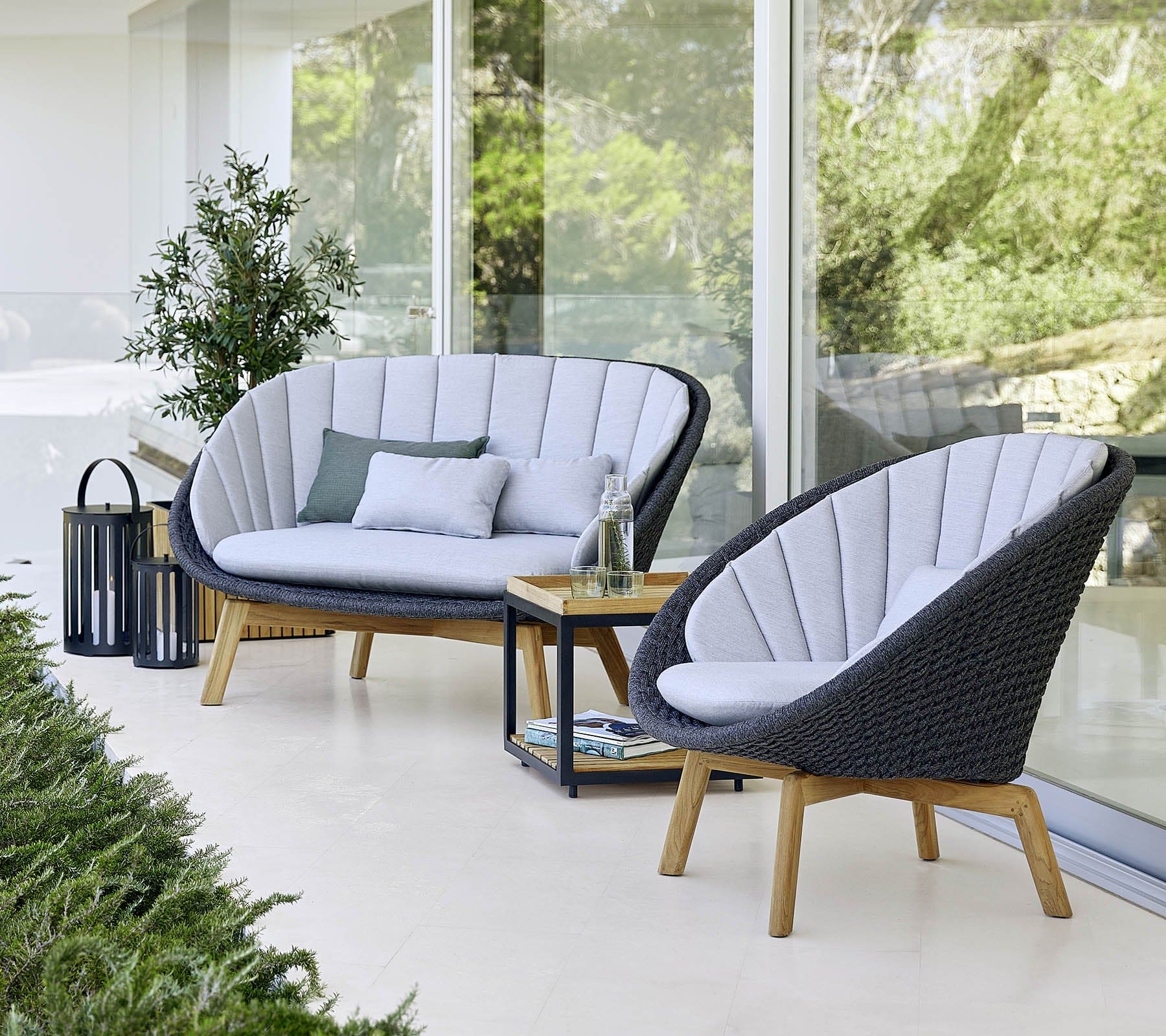  Boxhill's Peacock dark grey outdoor lounge chair with dark grey outdoor 2-seater sofa placed beside glass wall