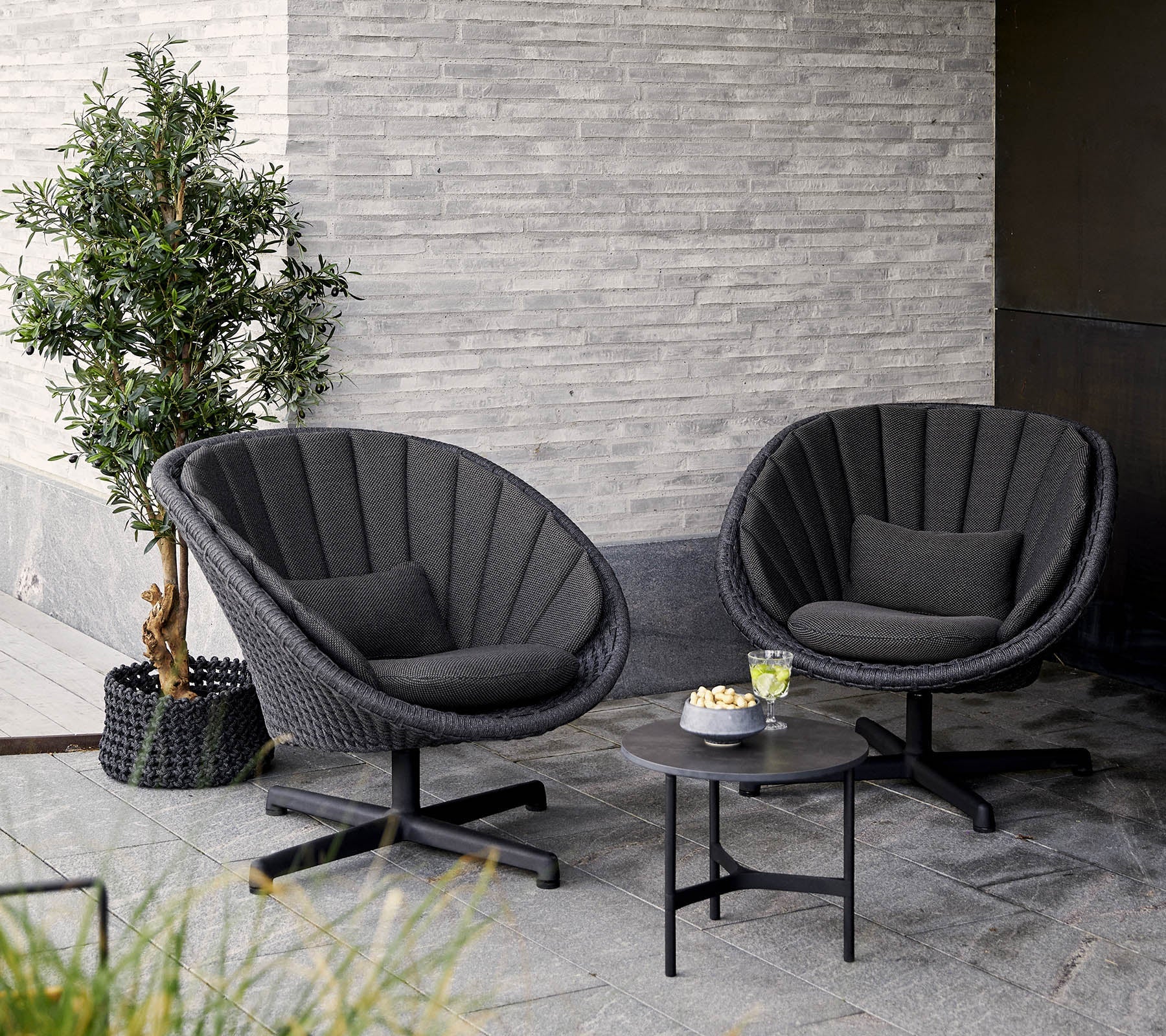  boxhill's peacock dark grey outdoor swivel lounge chair with small dark grey outdoor round table placed in patio