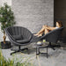boxhill's peacock dark grey outdoor swivel lounge chair with a woman sitting on it and a small dark grey outdoor round table