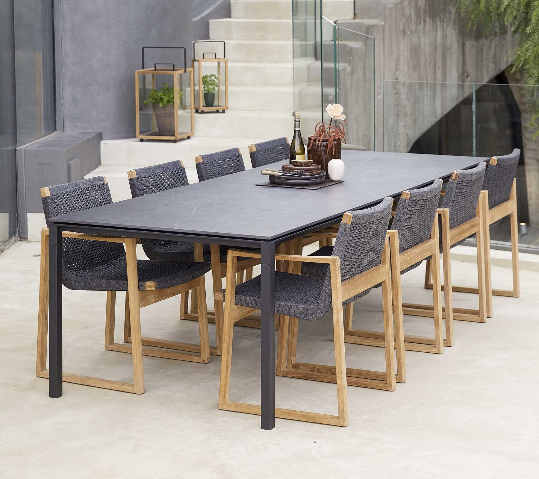 Boxhill's Pure dark grey aluminum outdoor dining table with teak dark grey dining chairs placed near the stairs