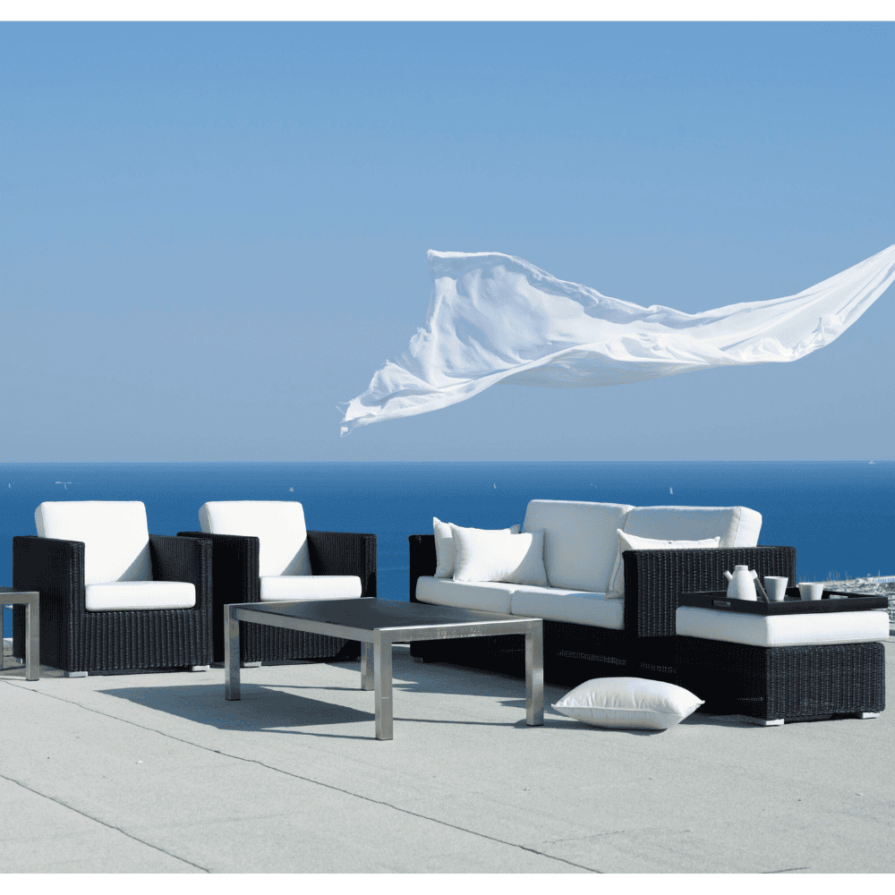 Boxhill's Chester Lounge Weave Coastal Chair Graphite lifestyle image with Chester 3-Seater Coastal Sofa and Chester Footstool, Weave Coffee Table with white fabric flying on air