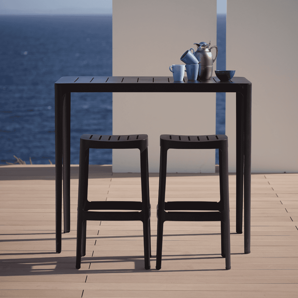 Boxhill's Cut High Outdoor Bar Table Black lifestyle image with Cut High Outdoor Bar Chair on wooden platform