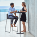 Boxhill's Go Outdoor Round Aluminum Bar Table Lava Grey lifestyle image with a man sitting on a bar chair and a woman standing having a chat