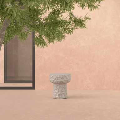 A concrete side table that has an abstract honeycomb texture reminiscing hammered metal.