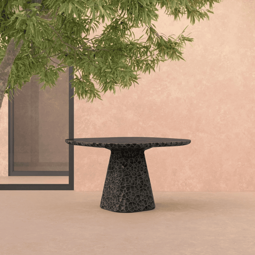 A concrete square shaped dining table that has an abstract honeycomb texture reminiscing hammered metal.