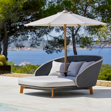 Boxhill's Peacock grey outdoor daybed with small teak table and white parasol on it placed beside the pool