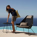 Boxhill's Breeze Highback Outdoor Chair Black lifestyle image with woman standing beside the pool