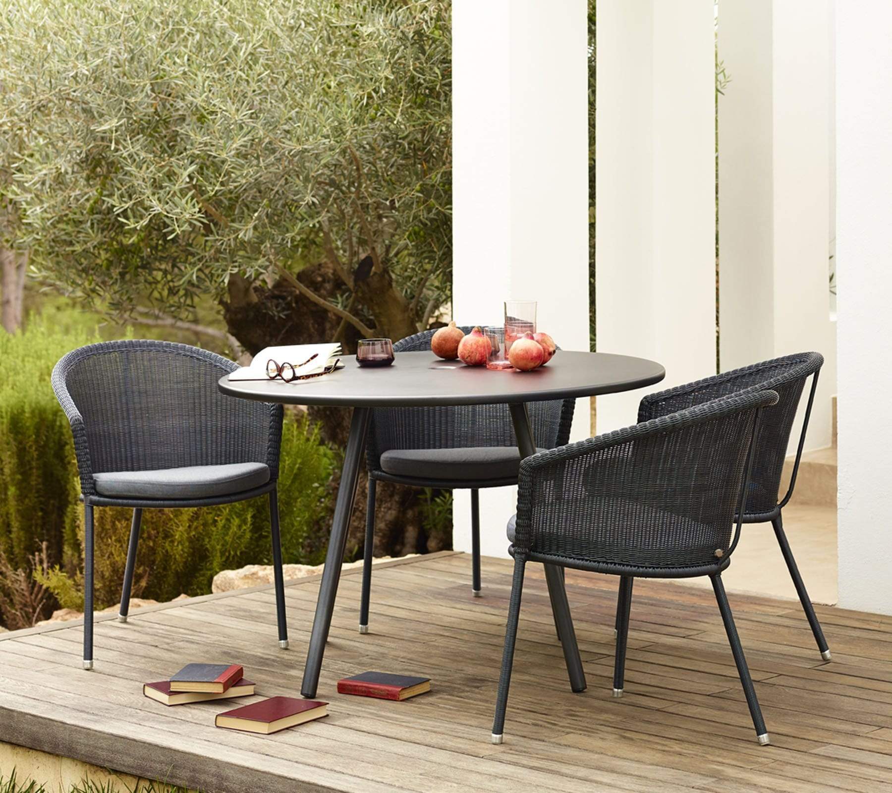  Boxhill's Trinity dark grey outdoor stackable chair with dark grey round dining table placed on wooden platform