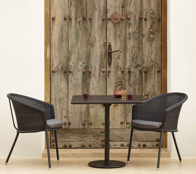  Boxhill's Trinity dark grey outdoor stackable chair with brown rectangular table placed beside vintage wardrobe