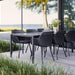 Boxhill's Vibe black outdoor armchair with dark grey outdoor dining table placed on wooden platform beside glass wall