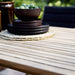 Boxhill's Flip Folding Outdoor Teak Dining Table with plates and bow on top, close up view