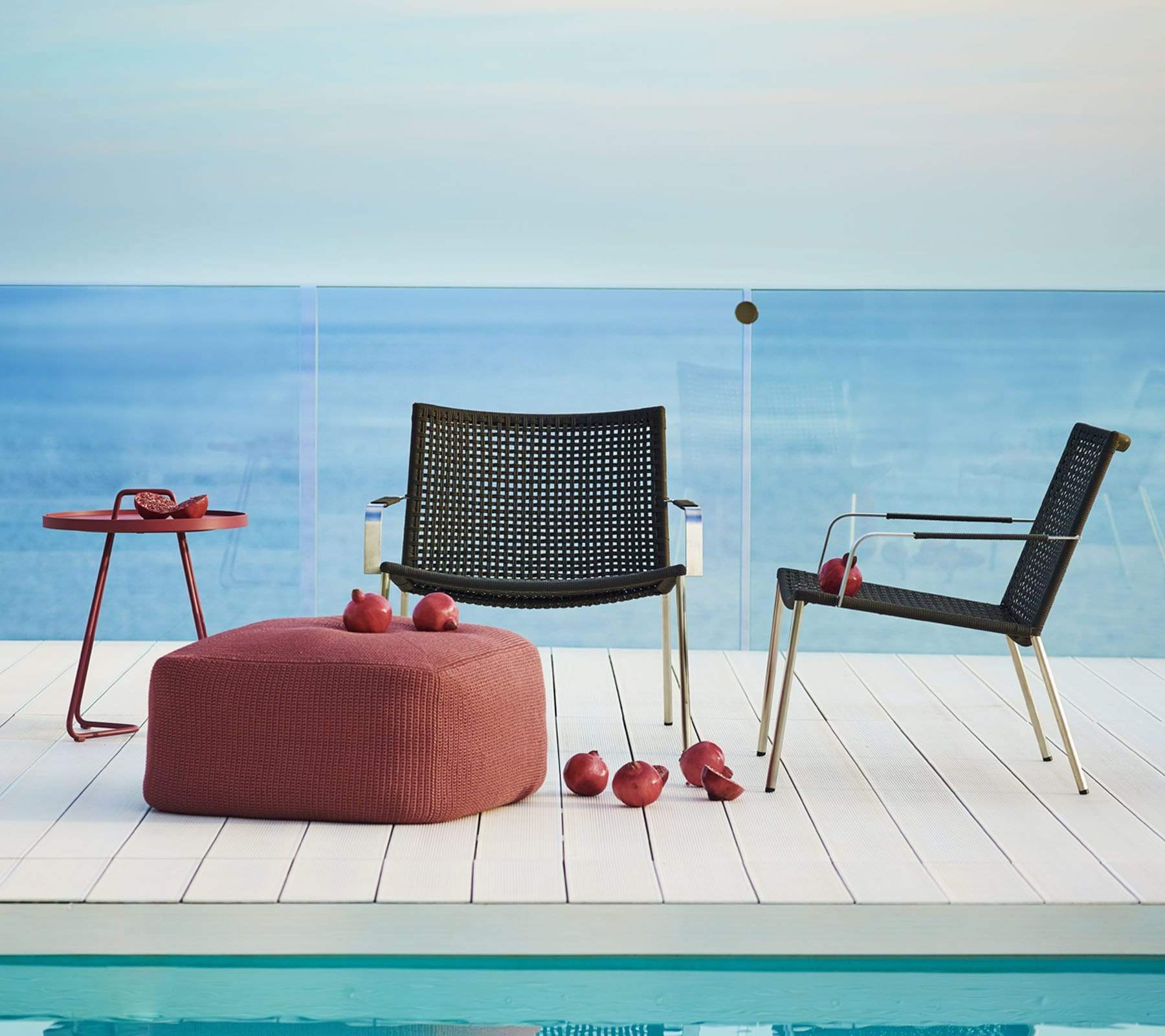 Boxhill's Straw dark grey outdoor lounge chair stainless steel frame with red round side table and red footstool placed on poolside