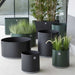 Boxhill's lava grey and dark green outdoor round medium modern planter box with large round and rectangular modern planter box placed in patio
