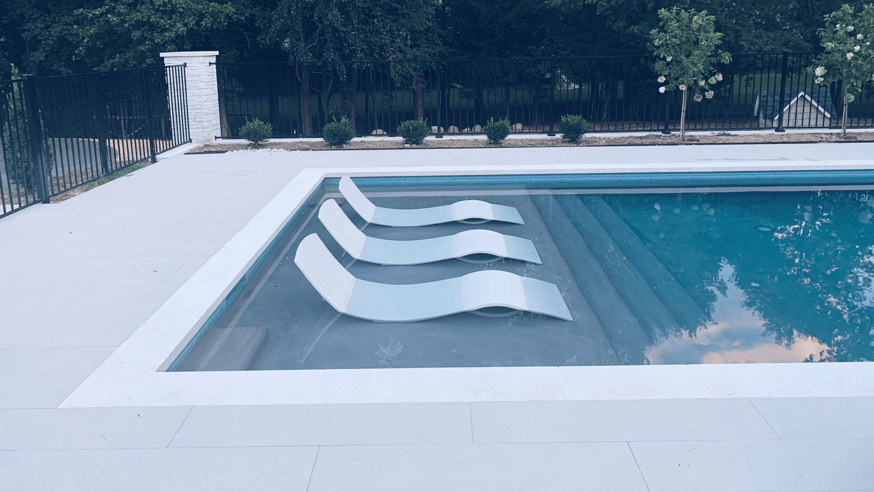 Three in-pool concrete chaise loungers on a pool tanning ledge.