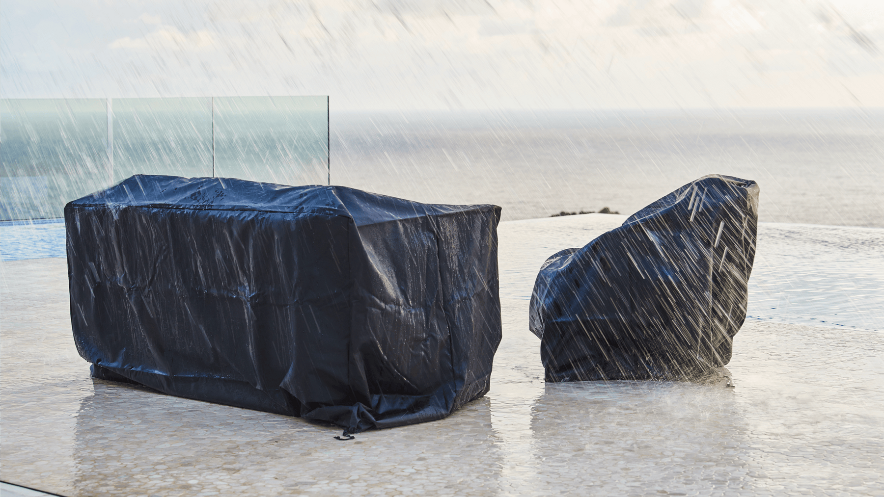 Outdoor furniture is protected from pouring rain with professionally fitted black covers.