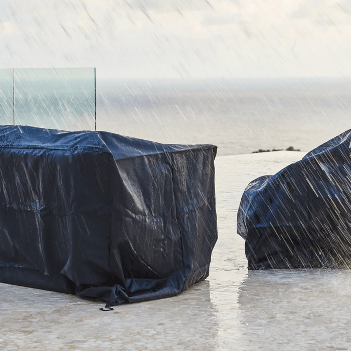 Outdoor furniture is protected from pouring rain with professionally fitted black covers.