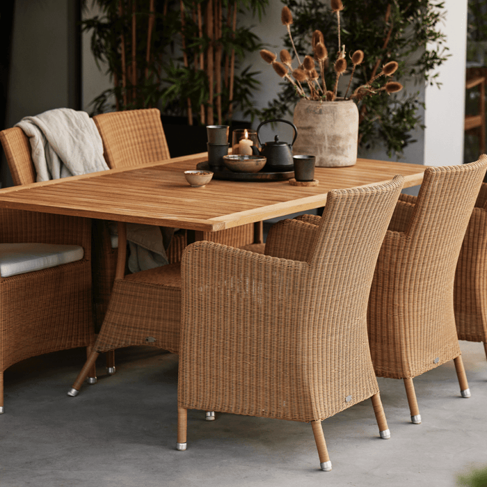 Danish loom-weave style outdoor dining chairs around teak table.