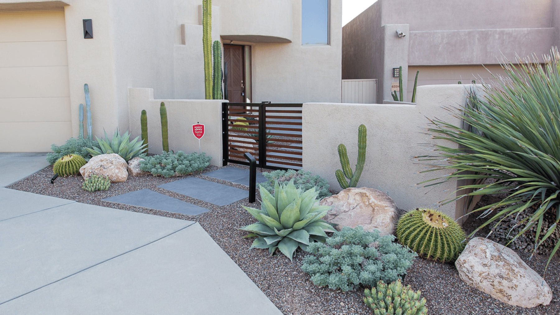 Desert landscaping at the front gate features a subtle pastel color palette.