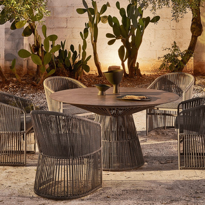 Curved woven dining armchairs in a desert garden at night.