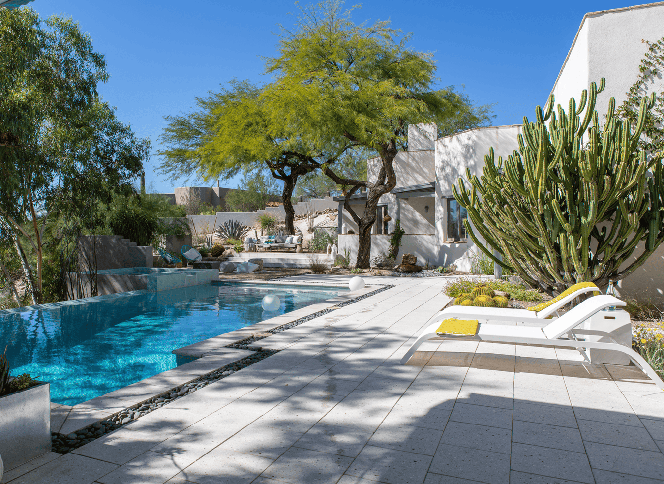 Desert patio and pool with white chaise lounge chairs.