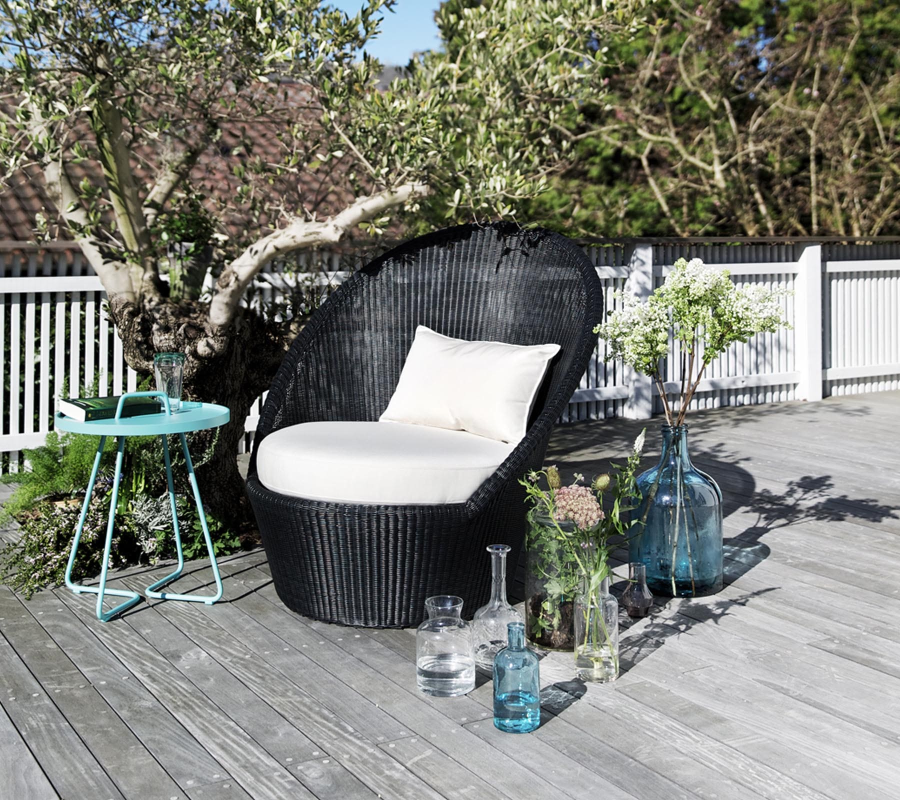 Boxhill's Kingston Sunchair Lounge with Wheels lifestyle image on wooden platform beside of the small tree with small round table and bottle container with plants at the side