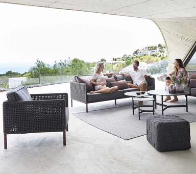 Boxhill's Encore 3-Seater Sofa lifestyle image at patio with Encore 2-Seater Outdoor Grey Sofa, Encore Outdoor Single Seater Grey Sofa and Cube Outdoor Footstool with 3 people sitting down
