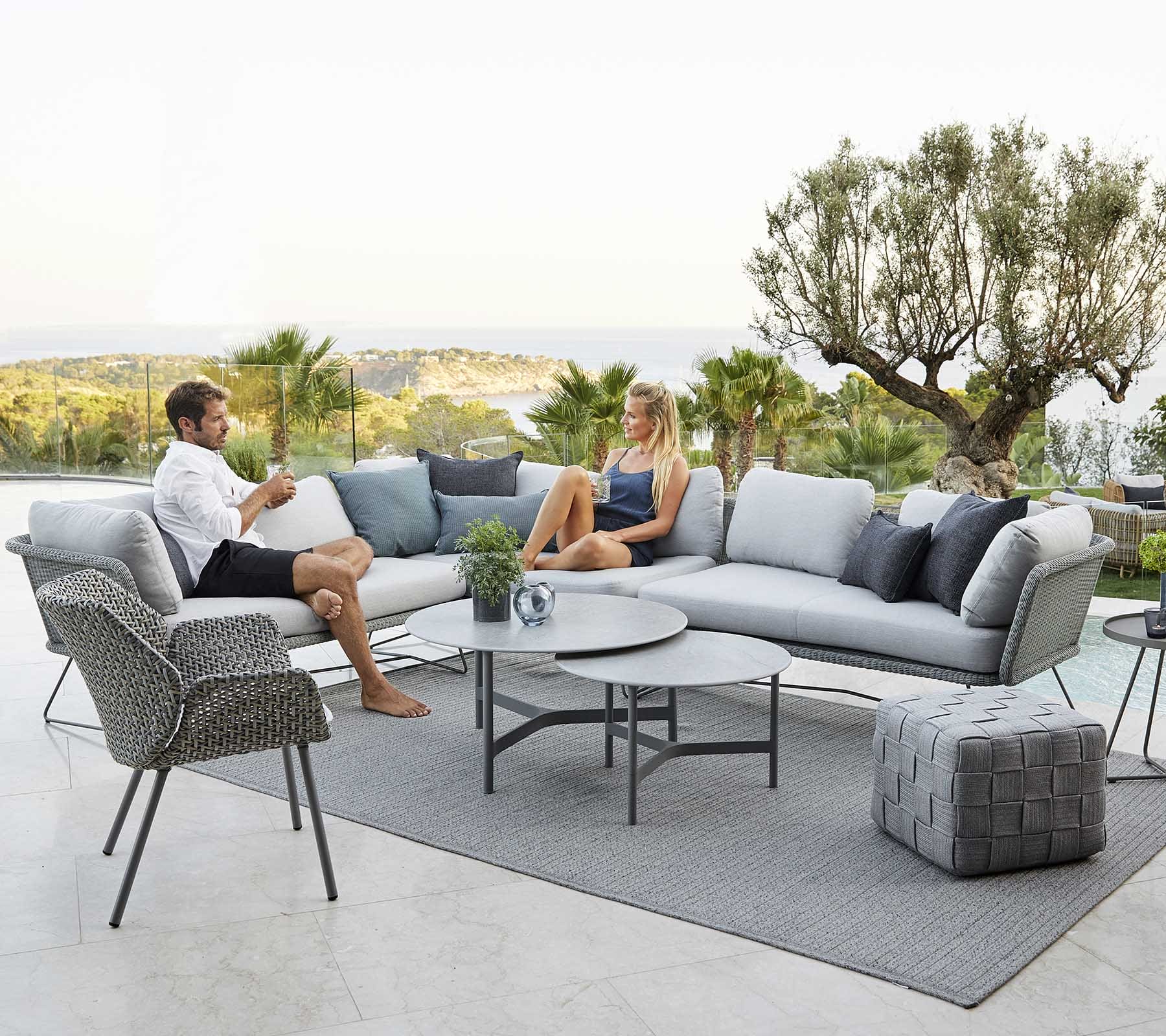 Boxhill's Horizon 2-Seater Outdoor Right Module Sofa lifestyle image together with Horizon 2-Seater Outdoor Left Module Sofa beside the pool with a man and a woman sitting down having a chat