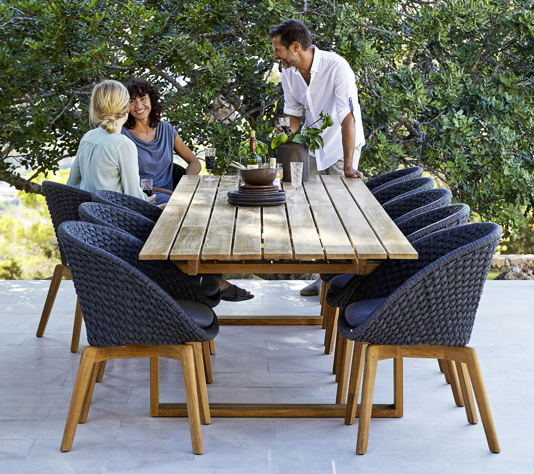 Boxhill's Endless Outdoor Rectangular Dining Table lifestyle image with dining chairs and 3 people having a chat