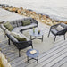Boxhill's Ocean Outdoor Corner Sofa Module lifestyle image with other Ocean Module Sofa and Chair Collection, and 2 round table on wooden platform beside rocky seashore