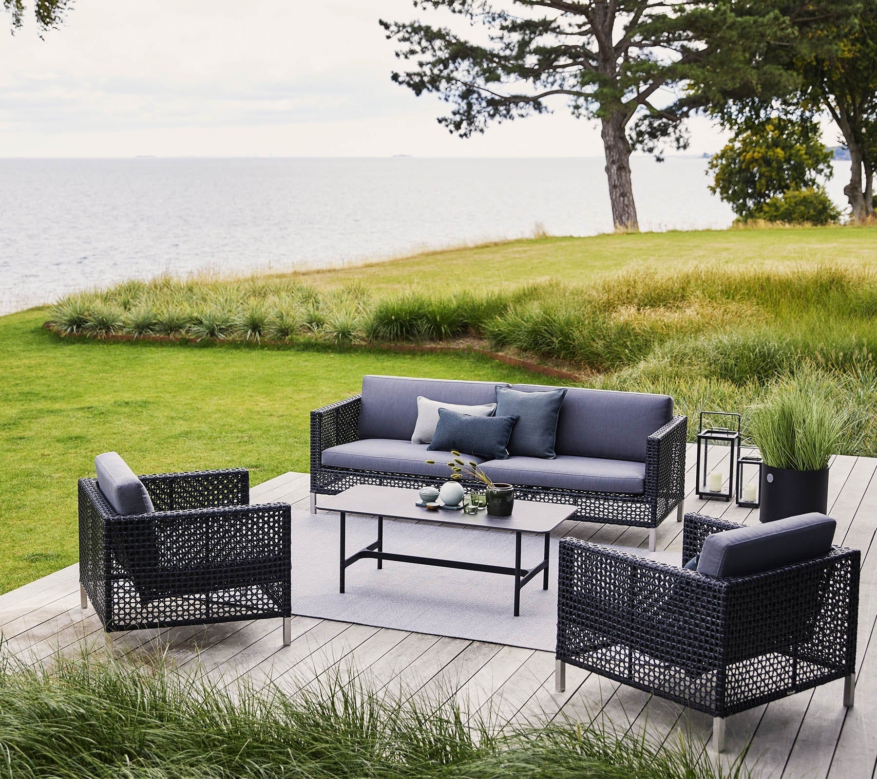 Boxhill's Connect 3-Seater Weave Sofa Graphite lifestyle image with Connect Lounge Chair on wooden platform at the garden