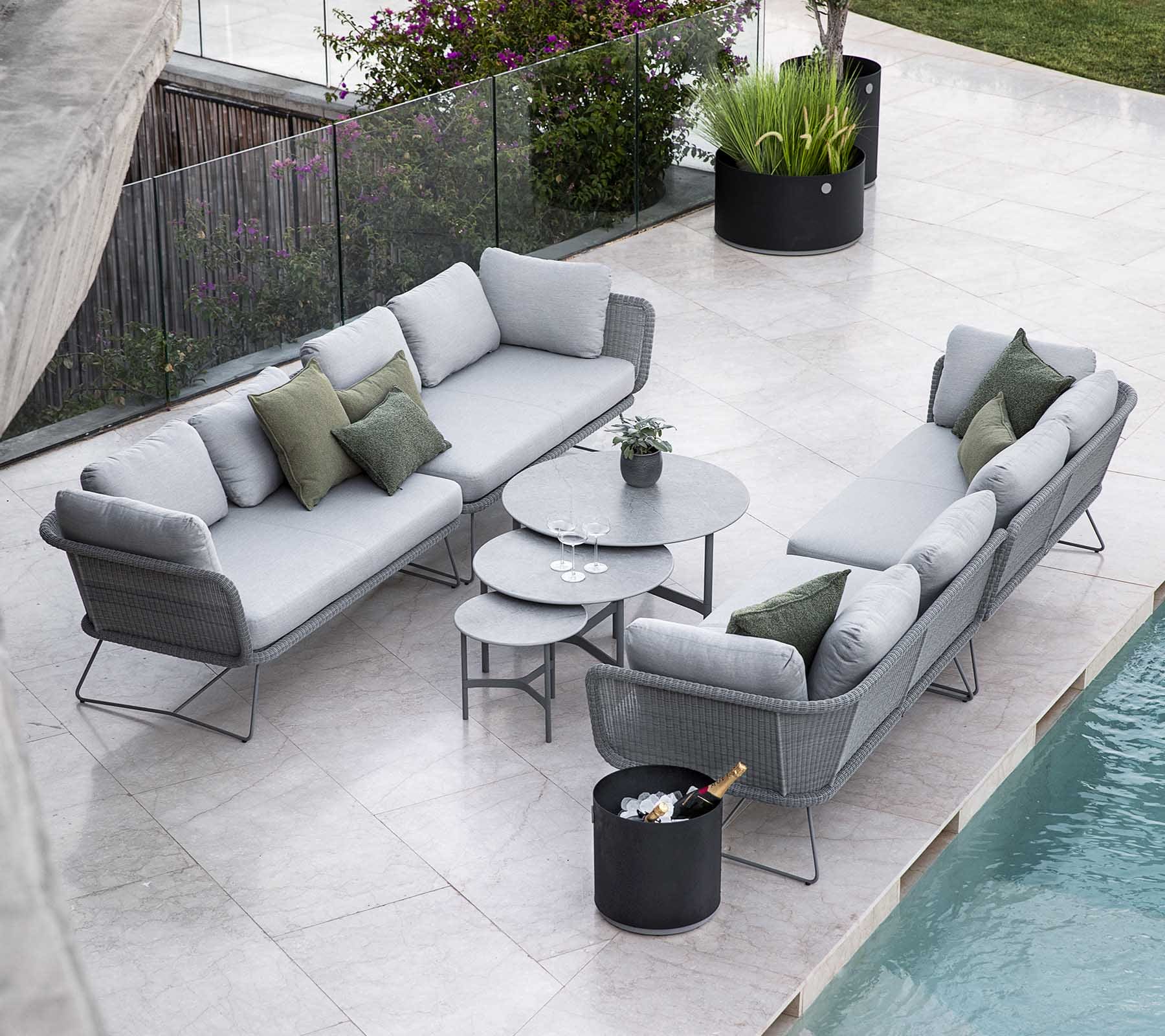 Boxhill's Horizon 2-Seater Outdoor Left Module Sofa lifestyle image together with Horizon 2-Seater Outdoor Right Module Sofa at poolside with 3 different sizes of round table at the center