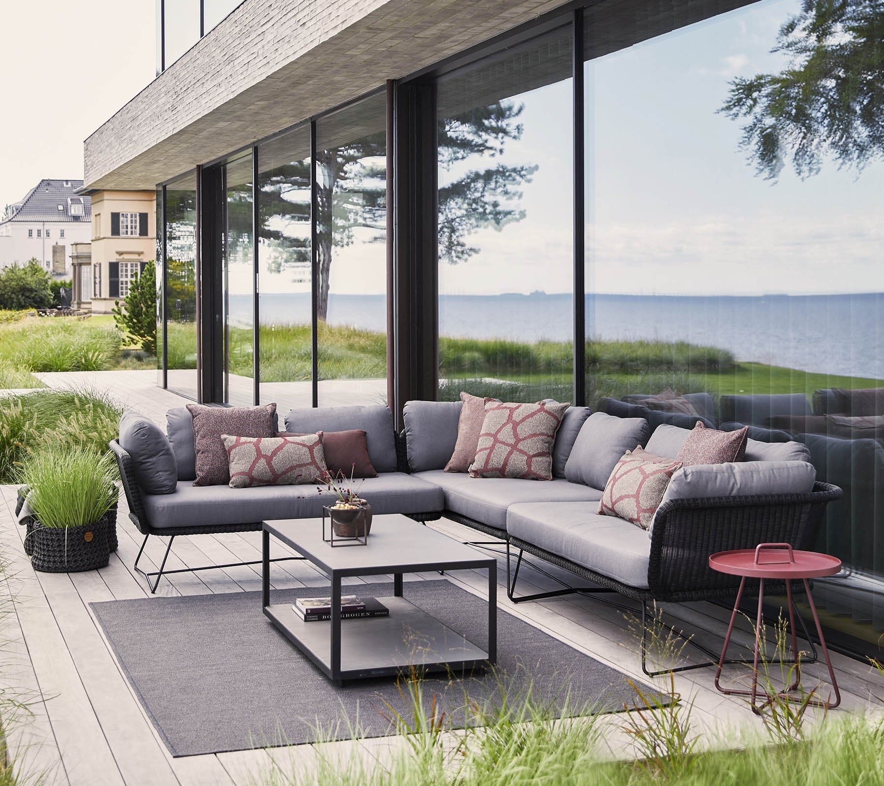 Boxhill's Horizon 2-Seater Outdoor Left Module Sofa lifestyle image together with Horizon 2-Seater Outdoor Right Module Sofa beside glass wall at patio, with rectangular table at the center and a small round side table at the side