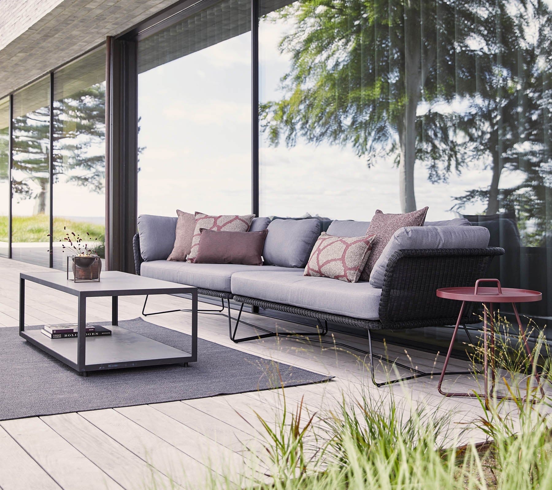 Boxhill's Horizon 2-Seater Outdoor Left Module Sofa lifestyle image together with Horizon 2-Seater Outdoor Right Module Sofa beside glass wall at patio, with rectangular table in front and a small round side table at the side
