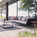 Boxhill's Horizon 2-Seater Outdoor Left Module Sofa lifestyle image together with Horizon 2-Seater Outdoor Right Module Sofa beside glass wall at patio, with rectangular table in front and a small round side table at the side