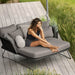 Boxhill's Horizon Outdoor Daybed lifestyle image on wooden platform with a woman sitting down beside grassy field