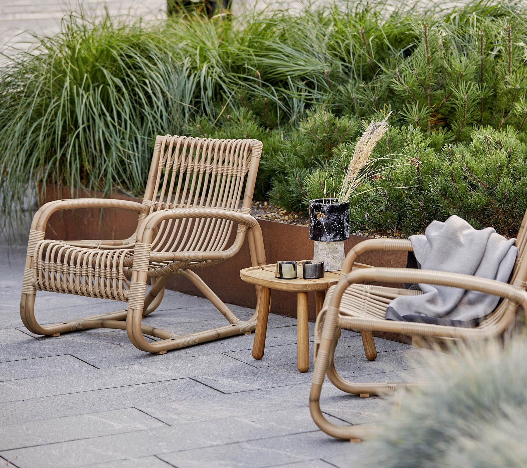 Boxhill's Curve Lounge Weave Outdoor Chair Natural lifestyle image with side table at patio