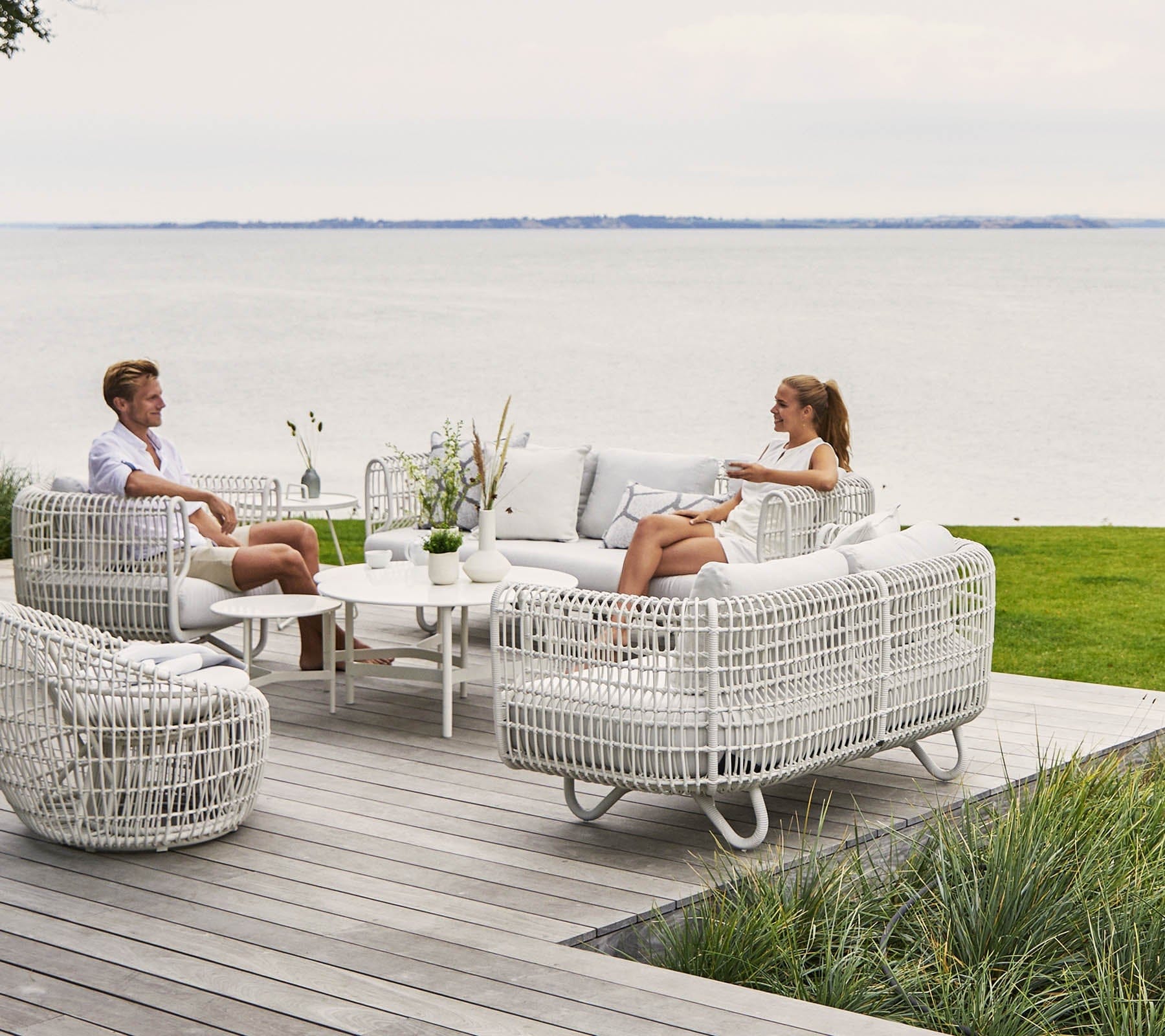 Boxhill's Nest Sofa Outdoor 3 Seater lifestyle image at patio with man and a woman sitting down having a chat