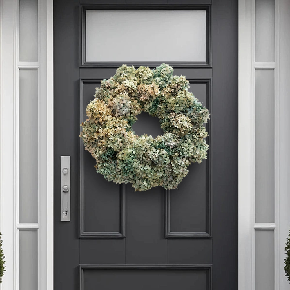 Decorative wreath made of dried pastel-toned hydrangea flowers hanging on a dark gray front door.