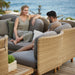 Boxhill's Arch Outdoor Corner Sofa w/ Teak Coffee Table 2 lifestyle image with man and woman sitting down