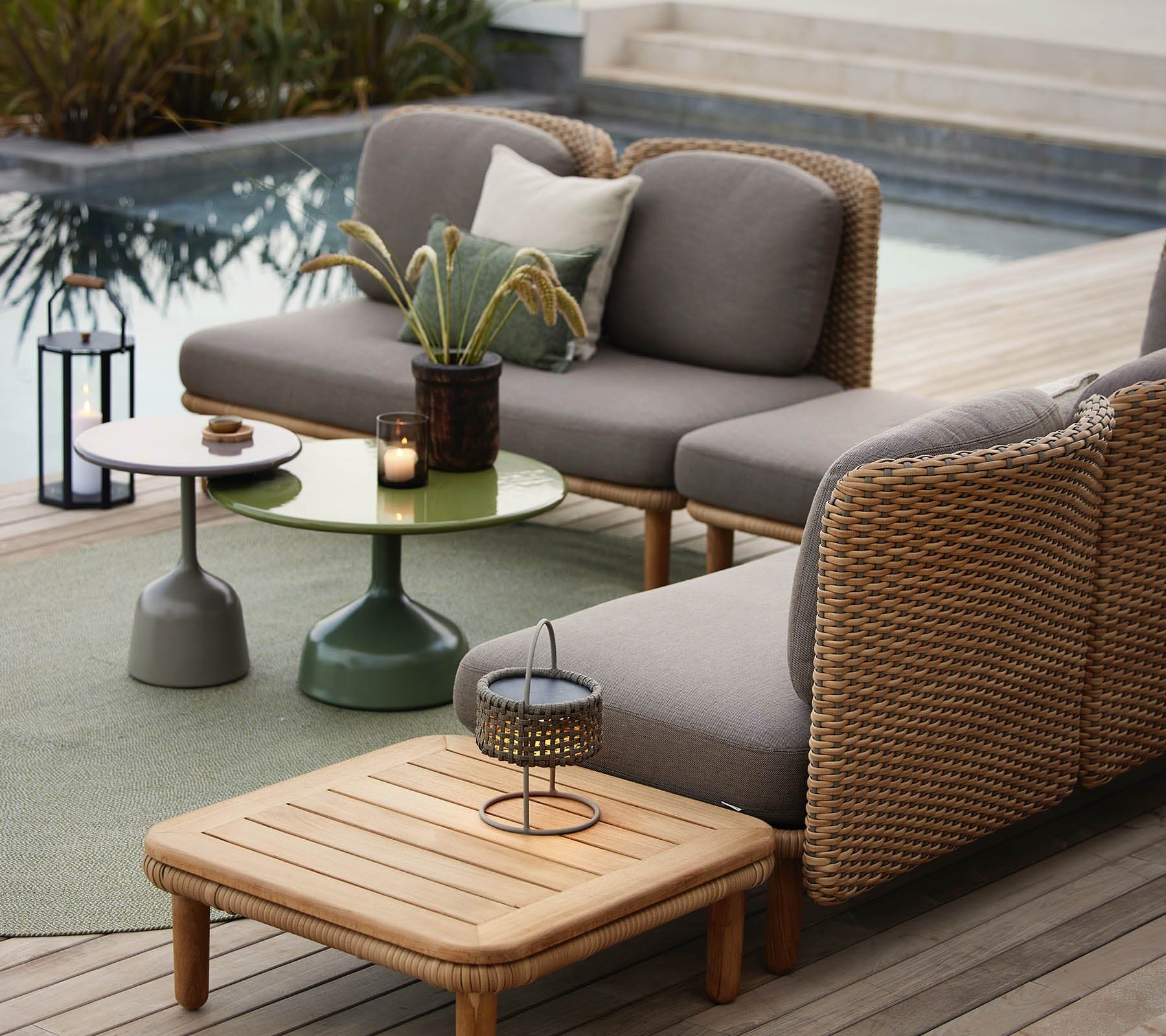 Boxhill's Illusion Outdoor Lamp | With Handle lifestyle image at top of Arch Outdoor Coffee Table, with Glaze Outdoor Round Coffee Table and Arch Sofa Collection at poolside